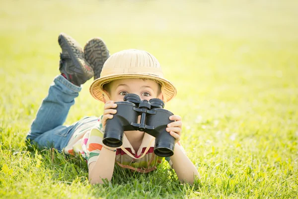 Felice bambino sorridente con cappello giocare con il binocolo in un giardino — Foto Stock