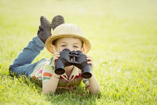 Felice bambino sorridente con cappello giocare con il binocolo in un giardino — Foto Stock