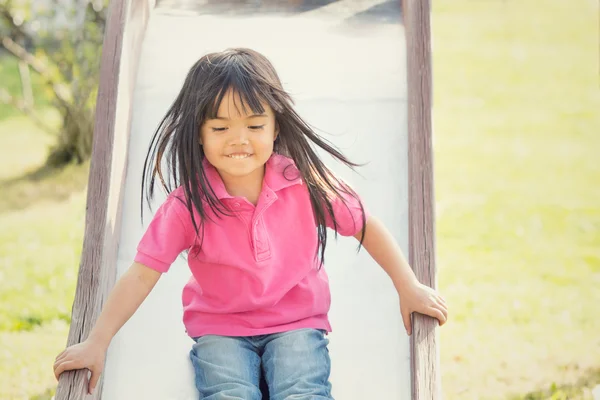 Счастливый улыбчивый ребенок играет с горкой в парке — стоковое фото