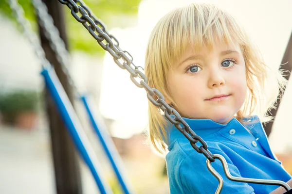 Happy smiling blond child play with seesaw in a park — Stock Photo, Image