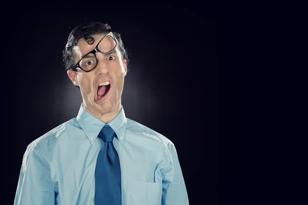 Nerd businessman with glasses make funny face isolated on black Stock Image