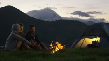 Grup üç arkadaşıyla birlikte açık doğa dağda kamp ateşi ile Isınma