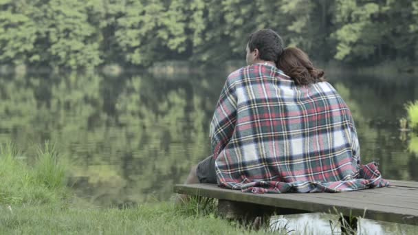 Jovem casal romântico na natureza sentado no lago molhe olhar para o panorama — Vídeo de Stock