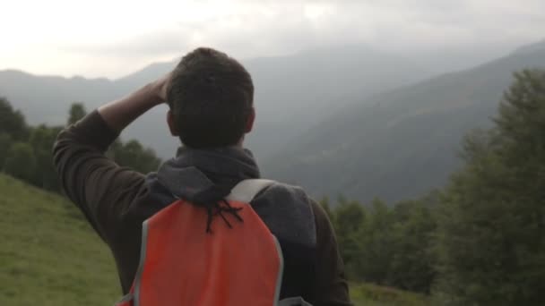 Hombre joven con una mochila vintage roja está caminando al aire libre en el camino de la montaña — Vídeos de Stock