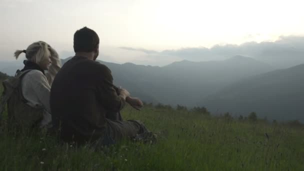 Jeune couple romantique assis sur l'herbe regarde au panorama — Video