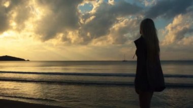 Genç güzel sarışın kadın siluet günbatımında kıyısında yürümek