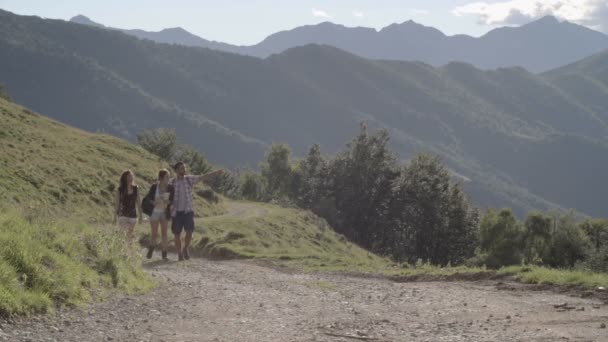 Genç arkadaşlar dağ açık bir yolda kamera doğru hiking — Stok video