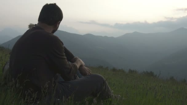 Junges romantisches Paar sitzt im Gras und beobachtet das Panorama — Stockvideo