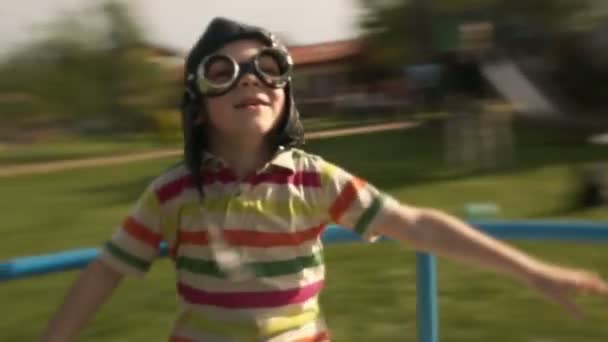 Child wearing aviator glasses is playing in summer day on carousel — Stock Video