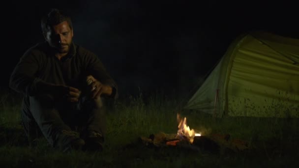 Jovem homem bonito está acampando à noite — Vídeo de Stock