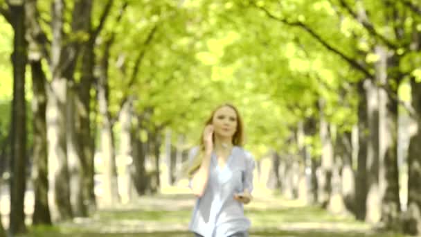 Krásná blonďatá dívka chodí v městském parku poslechu hudby — Stock video