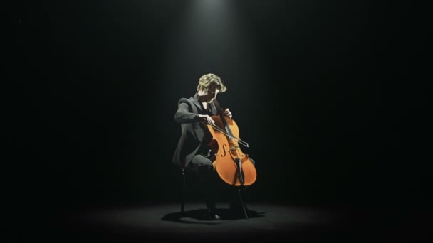 Виолончелист настраивает свою виолончель один на сцене — стоковое видео
