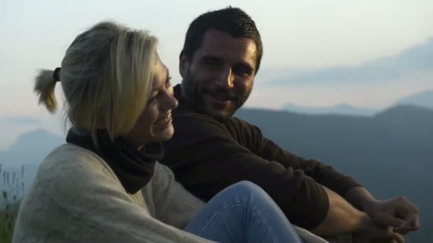 Молодая красивая романтическая пара, сидящая на траве, смотрит на панораму — стоковое видео
