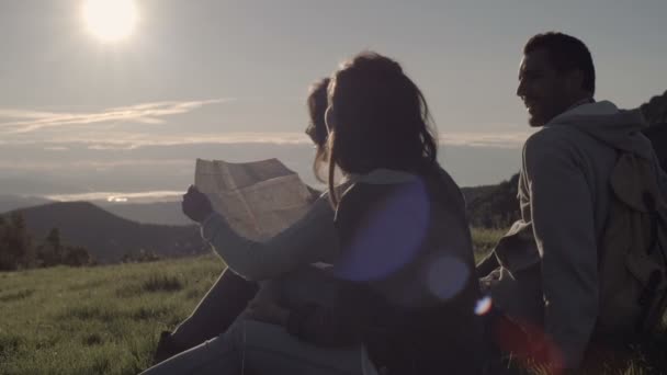 Jóvenes amigos haciendo camping mira el mapa en montaña al aire libre — Vídeo de stock
