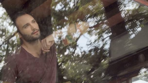 Красивий чоловік, дивлячись на вікно кидка — стокове відео