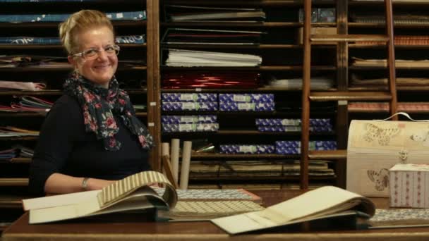 Senior woman is selecting pieces of paper in front of wooden shelf — Stock Video