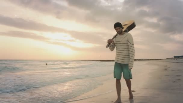 Vista frontal do jovem homem bonito caminhar ao longo do oceano praia à beira-mar — Vídeo de Stock