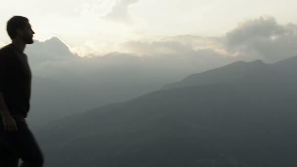 Joven hombre hermoso está caminando al aire libre en la montaña al atardecer — Vídeo de stock