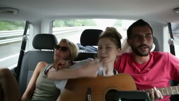 Tres jóvenes amigos se divierten cantando con la guitarra durante un viaje — Vídeos de Stock