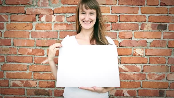 Joven mujer sonriente delante de la pared de ladrillo — Vídeos de Stock