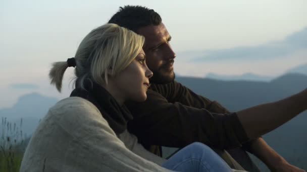 Young beautiful romantic couple seated on the grass is watching at panorama — Stock Video