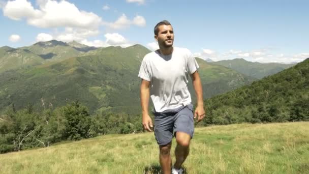 Вид спереди молодого человека, совершающего поход в горы на природе — стоковое видео