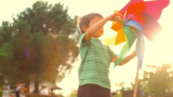 Niño feliz jugar con pinwheel colorido — Vídeos de Stock