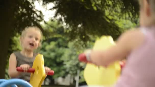 Feliz rubia hermanas están jugando al aire libre en hobbyhorse en el parque de la ciudad — Vídeos de Stock