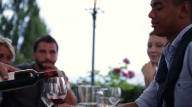 Young black man with his friends taste a red wine glasses poured from a water
