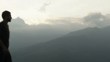 Genç güzel adam açık dağda günbatımında yürüyor