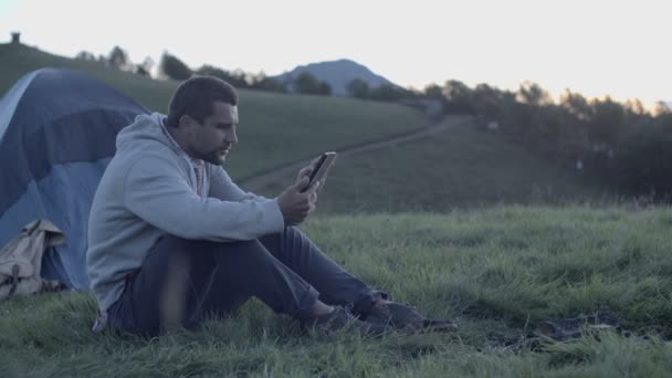 Mann benutzt Tablette im Gebirge bei Sonnenuntergang — Stockvideo