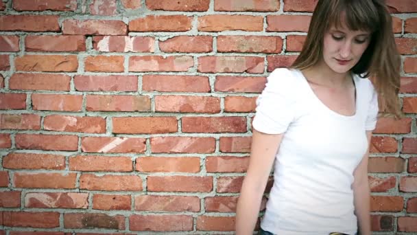 Jovem mulher sorridente na frente da parede de tijolo — Vídeo de Stock