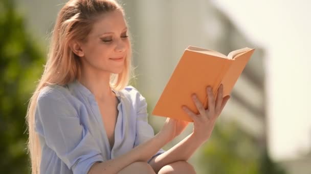 Young beautiful blonde girl in summer day is reading a book — Stock Video