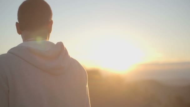 Vista trasera del hombre joven mirando el sol en la naturaleza montaña — Vídeos de Stock