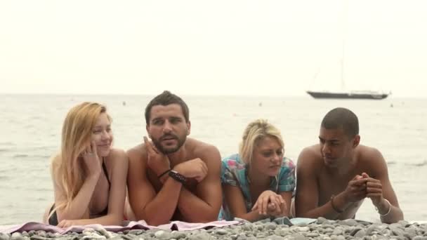 Vier multi-etnisch vrienden in zomerdag op het strand liggen — Stockvideo