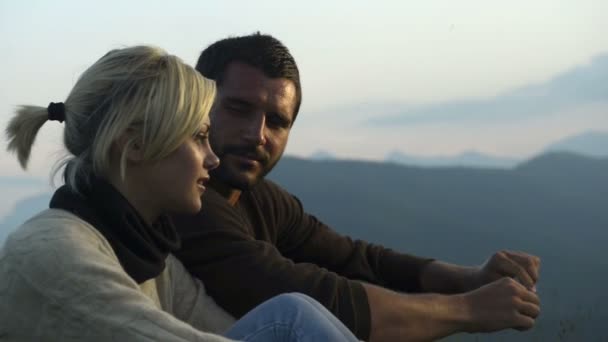 Unga vackra romantiska par sitter på gräset tittar på panorama — Stockvideo