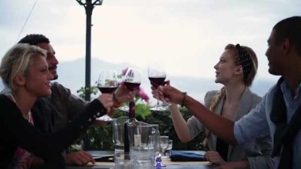 Cuatro amigos multiétnicos en el restaurante italiano en la noche hacen un brindis — Vídeo de stock
