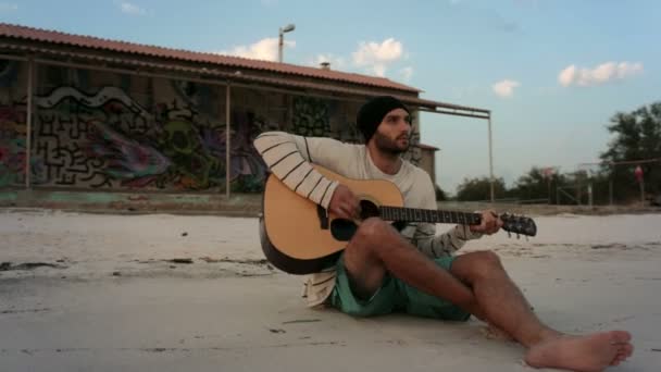 Caminhe ao redor jovem homem bonito tocando guitarra na praia do oceano à beira-mar — Vídeo de Stock