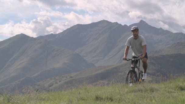 Giovane atletico uomo in giorno d'estate è in bicicletta all'aperto in montagna — Video Stock