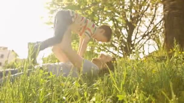 Glücklicher Familienvater und Sohn spielen an Sommertagen liegend — Stockvideo