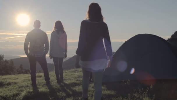 Jóvenes amigos haciendo camping mira al sol en la montaña al aire libre — Vídeo de stock