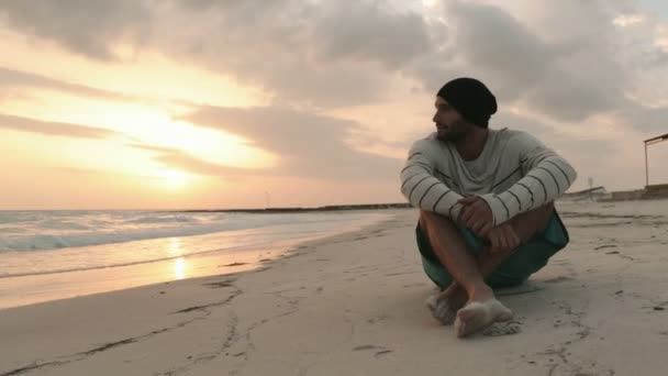 Joven hombre hermoso relajarse en la playa del océano al amanecer o al atardecer — Vídeos de Stock