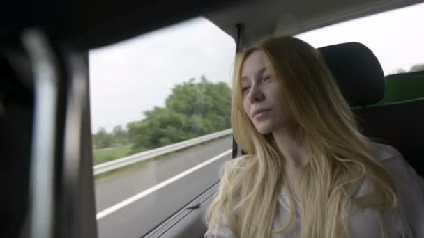 Jong mooi blond vrouw is kijken uit het raam — Stockvideo