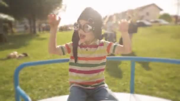 Niño con gafas de aviador está jugando en el día de verano en carrusel — Vídeos de Stock