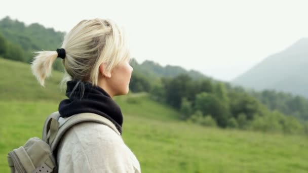 Joven hermosa mujer rubia está admirando el panorama en la montaña — Vídeos de Stock