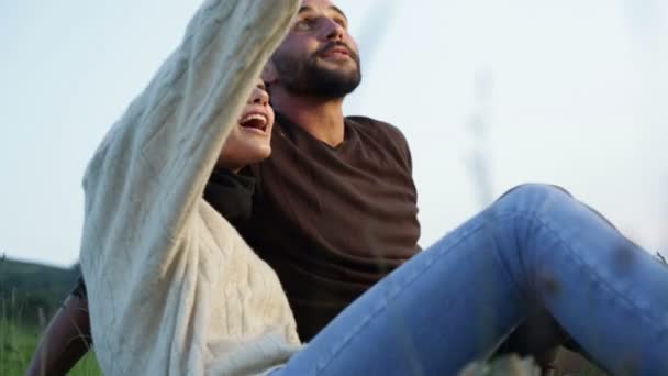 Unga vackra paret sitter på gräset tittar på panorama — Stockvideo