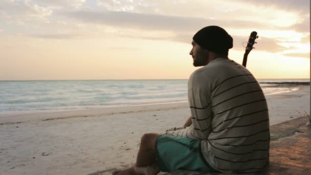 Giovane bellissimo uomo malinconico sulla spiaggia dell'oceano sul mare all'alba — Video Stock