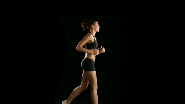 Woman running in dark studio — Stock Video