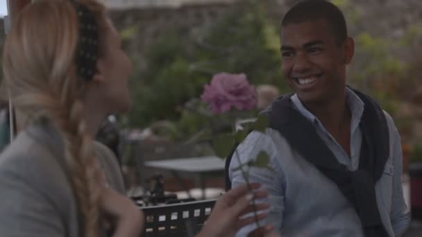 Joven hombre negro hermoso presente una rosa a una hermosa mujer rubia — Vídeo de stock