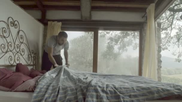 Junger Mann macht ein Bett — Stockvideo